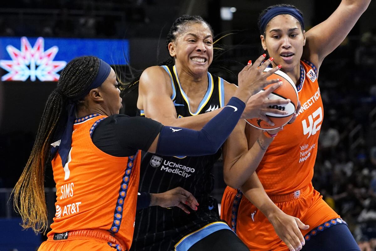 Chicago Sky forward Candace Parker, center, drives to the basket against Connecticut Sun guard Odyssey Sims, left, and center Brionna Jones during the second half of Game 2 in a WNBA basketball playoffs semifinal Wednesday, Aug. 31, 2022, in Chicago. The Sky won 85-77. (AP Photo/Nam Y. Huh)