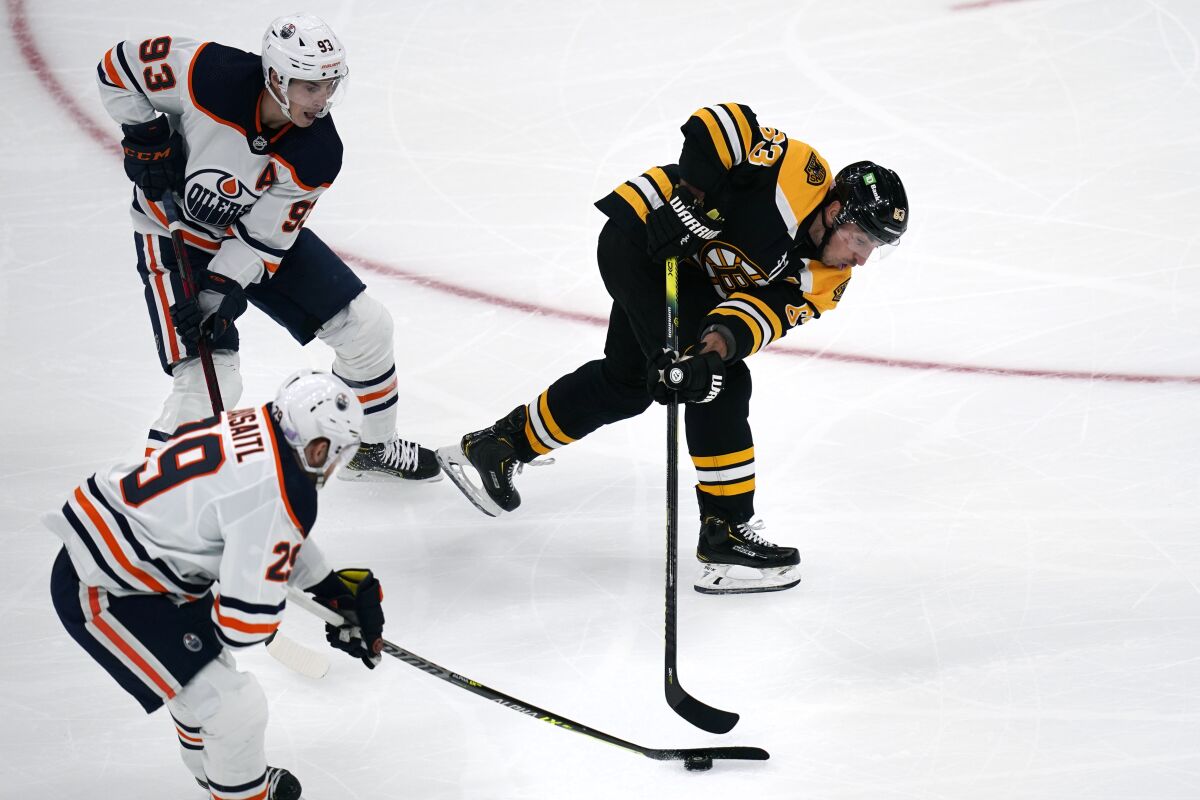 Edmonton Oilers center Leon Draisaitl (29) strips the puck away from Boston Bruins center Brad Marchand (63) during the first period of an NHL hockey game, Thursday, Nov. 11, 2021, in Boston. Oilers center Ryan Nugent-Hopkins (93) looks on. (AP Photo/Charles Krupa)