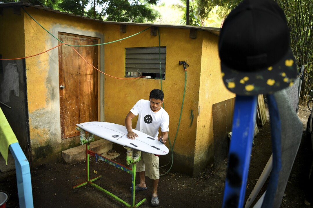 Local Alex Hernandez fixes a surfboard at Surf City in El Salvador. 