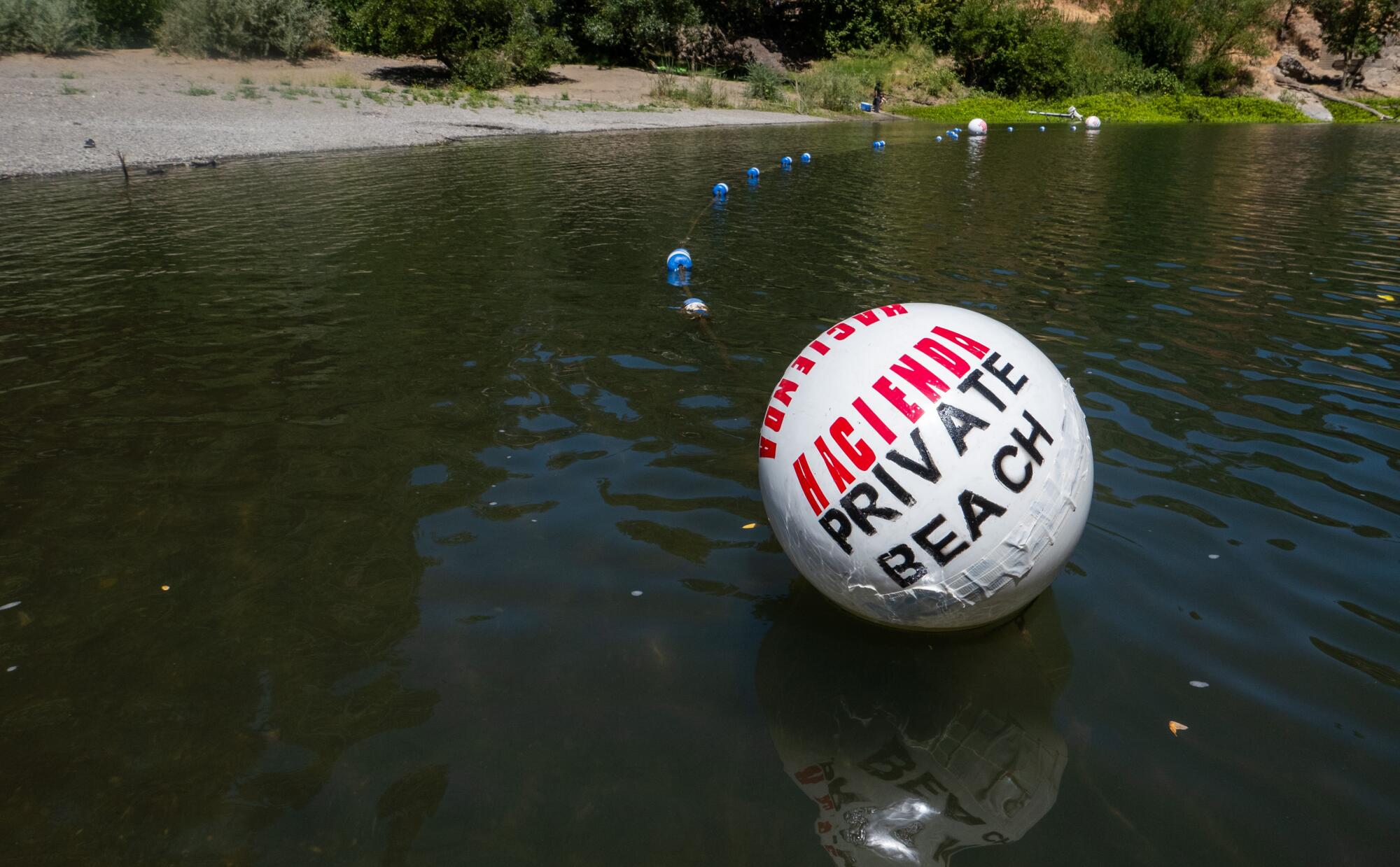 A white buoy labels a beach on the Russian River shoreline as private.