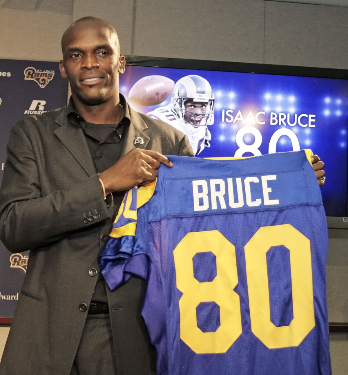 Isaac Bruce holds up his Rams jersey number at a 2010 news conference to announce his retirement.