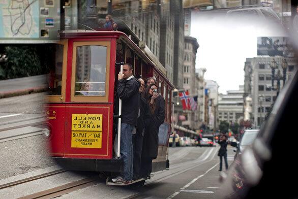 A San Francisco icon, a cable car, moves along Powell, reflected in a car mirror.