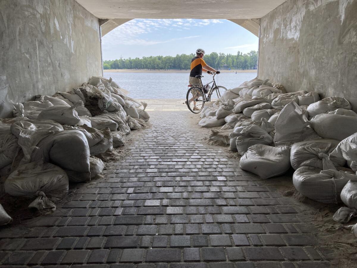 A person pushes a bicycle through a tunnel lined with sandbags