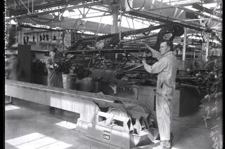 Assembly line workers assemble car parts at a Ford plant.