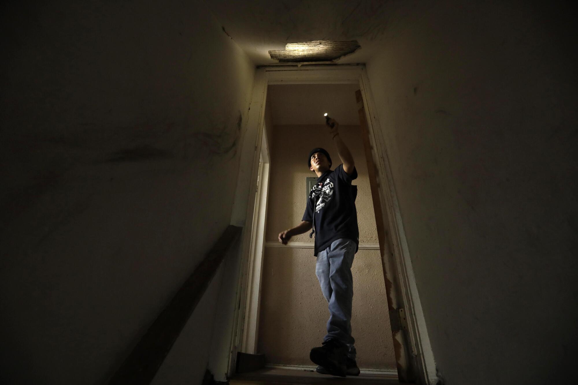 A man uses a flashlight to look at the ceiling