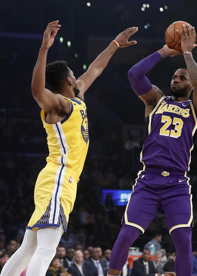 Lakers forward LeBron James shoots and scores over Warriors forward Glenn Robinson III in the first quarter.