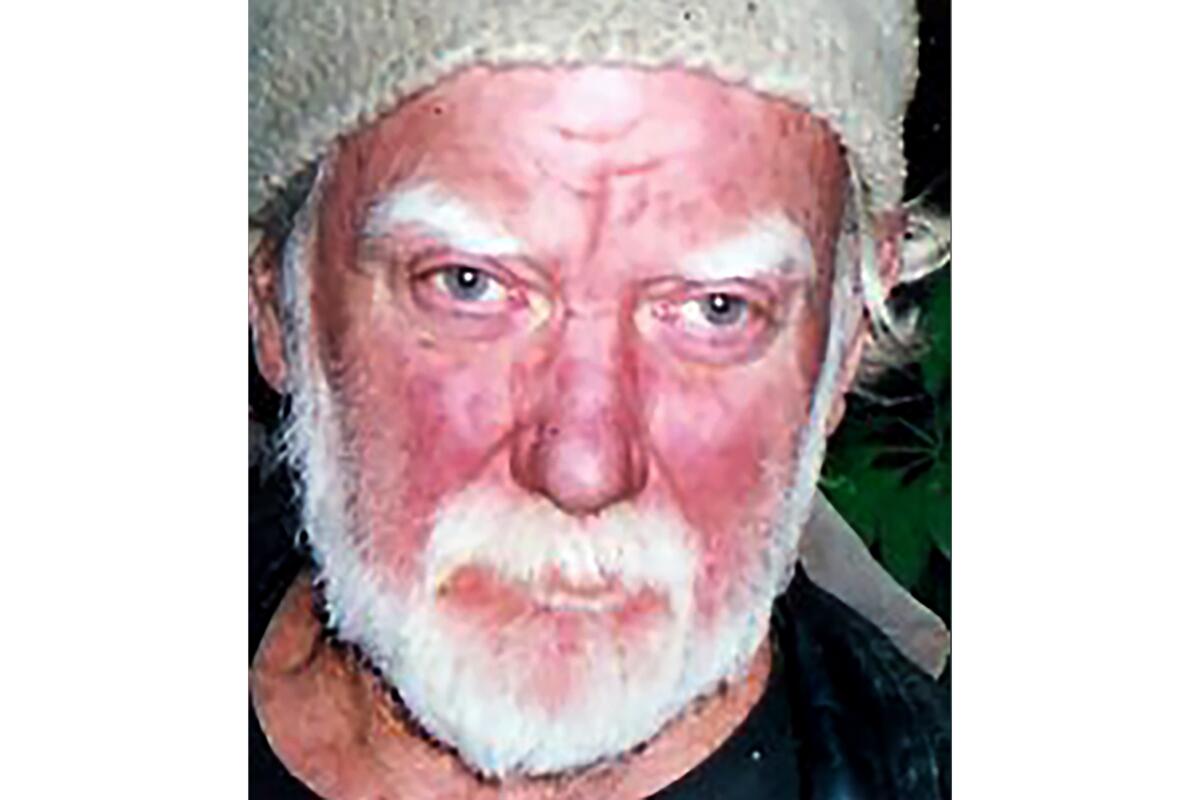 Mug shot of a man with white facial hair and a hat