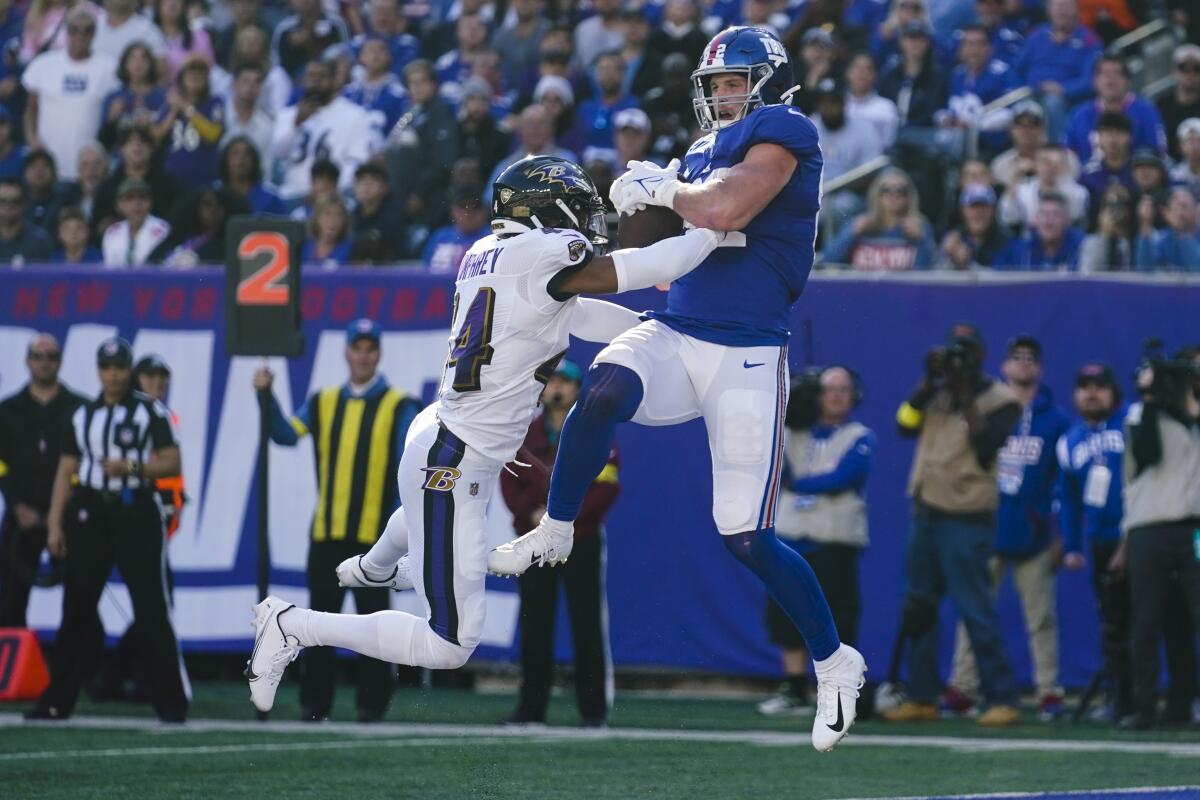 New York Giants' Daniel Bellinger, right, catches a pass for a touchdown in front of Baltimore Ravens' Marcus Peters (24) during the second half of an NFL football game Sunday, Oct. 16, 2022, in East Rutherford, N.J. (AP Photo/Seth Wenig)