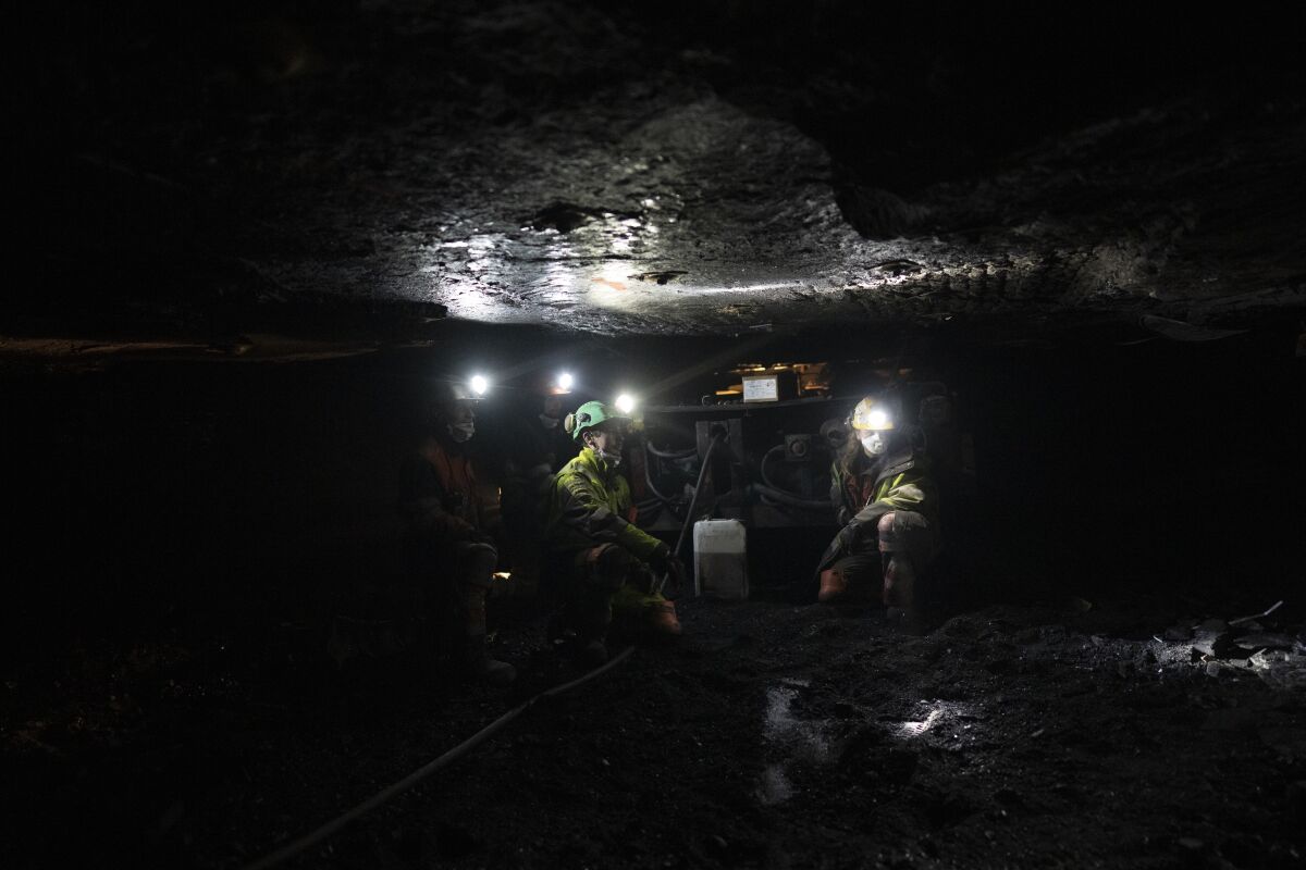 Coal miners refill a machine with oil at the bottom of a coal mine.