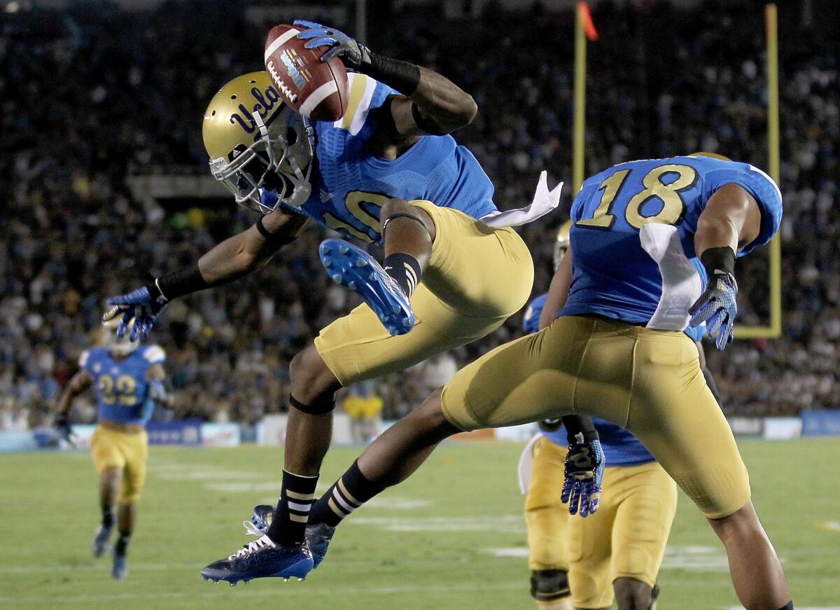 UCLA receiver Kenneth Walker III celebrates with teammate Thomas Duarte (18) after making a touchdown catch against Memphis in the first quarter.