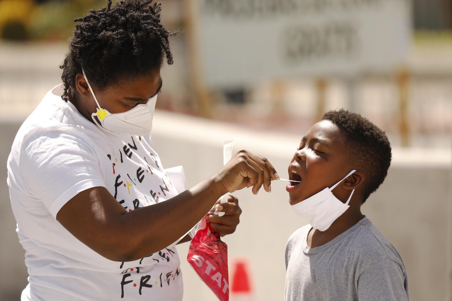 Cynthia Leonard helps her son with an oral swab test at a South L.A. test site.