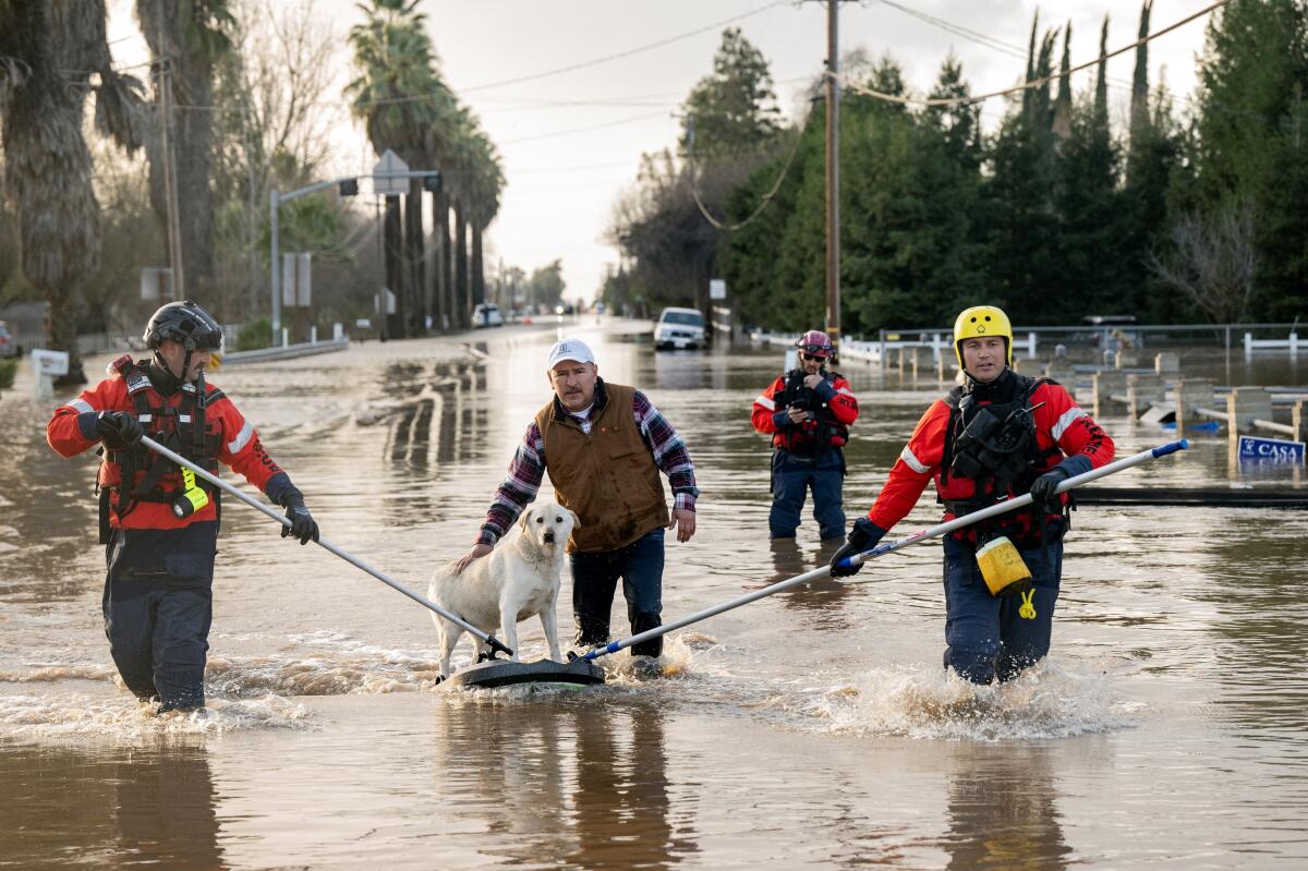 San Diego firefighters help Humberto Maciel rescue his dog from his flooded home in Merced, Calif., on Jan. 10.