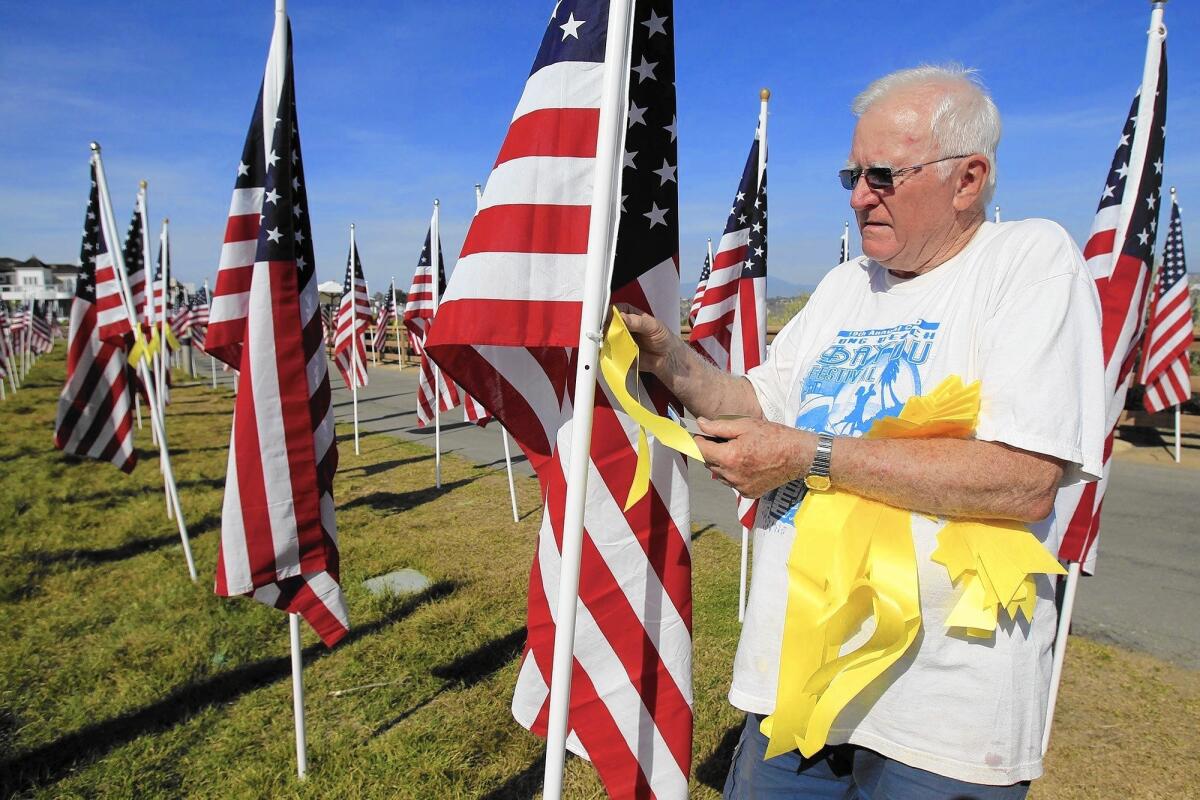 Ken DuFour of the Exchange Club of Newport Harbor places a yellow ribbon on one of 1,776 American flags at the 2014 Field of Honor at Castaways Park in Newport Beach. This year's Field of Honor, saluting military men and women in conjunction with Armed Forces Day, will be dedicated Saturday.