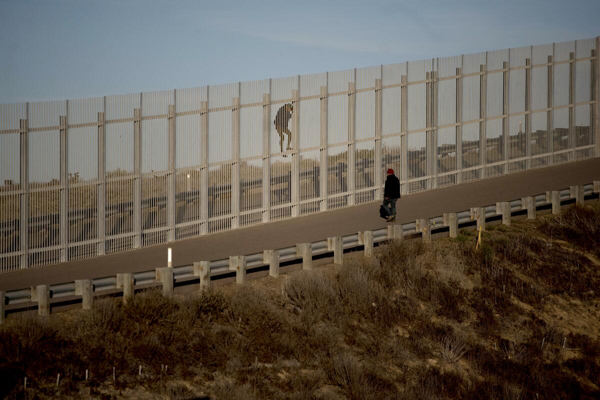 Immigrants try to cross a wall at the Tijuana border.
