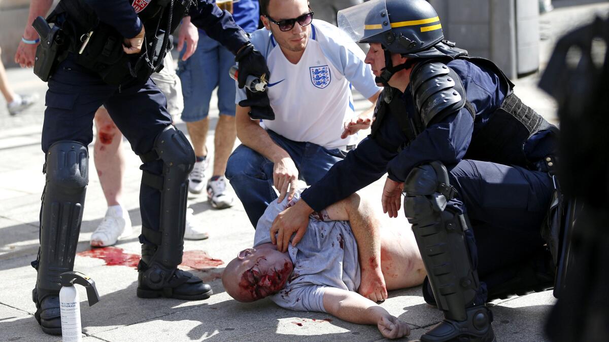 A man injured during clashes between soccer fans is assisted by police in Marseille.