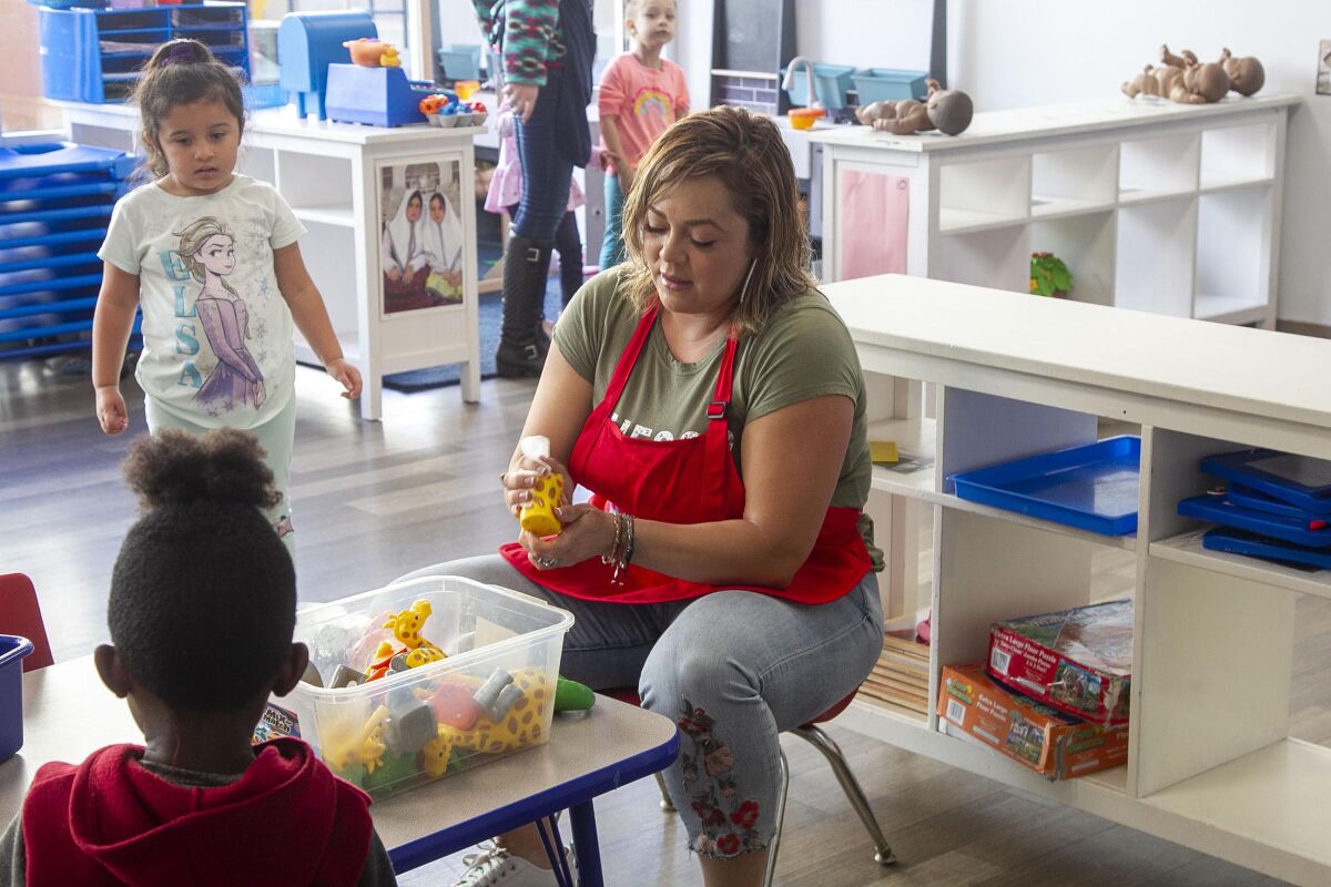 Consuelo Garcia sanitizes toys at the Children of the Rainbow child-care center in San Diego.