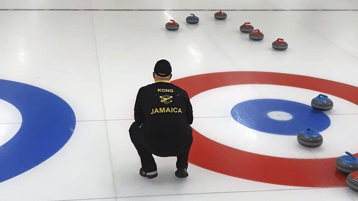 In this photo provided by Curling Jamaica, Jamaica's Ben Kong looks out at the sheet during a practice game against Hong Kong on Saturday, April 2, 2022, at the Unionville Curling Club in Markham, Ontario, Canada. The Jamaican curlers are sliding into the footsteps of the bobsledders that brought the tropical island nation to the Winter Olympics and became an international sensation. (Sandy Ewart/Curling Jamaica photo via AP)