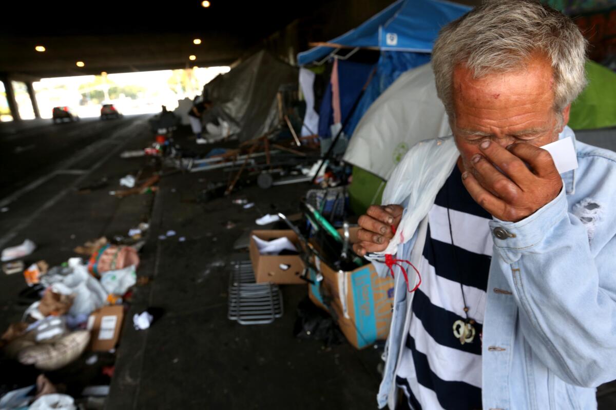 A man wipes his eyes on a sidewalk blocked with tents at a homeless encampment on Editors: Kaufman was not crying.
