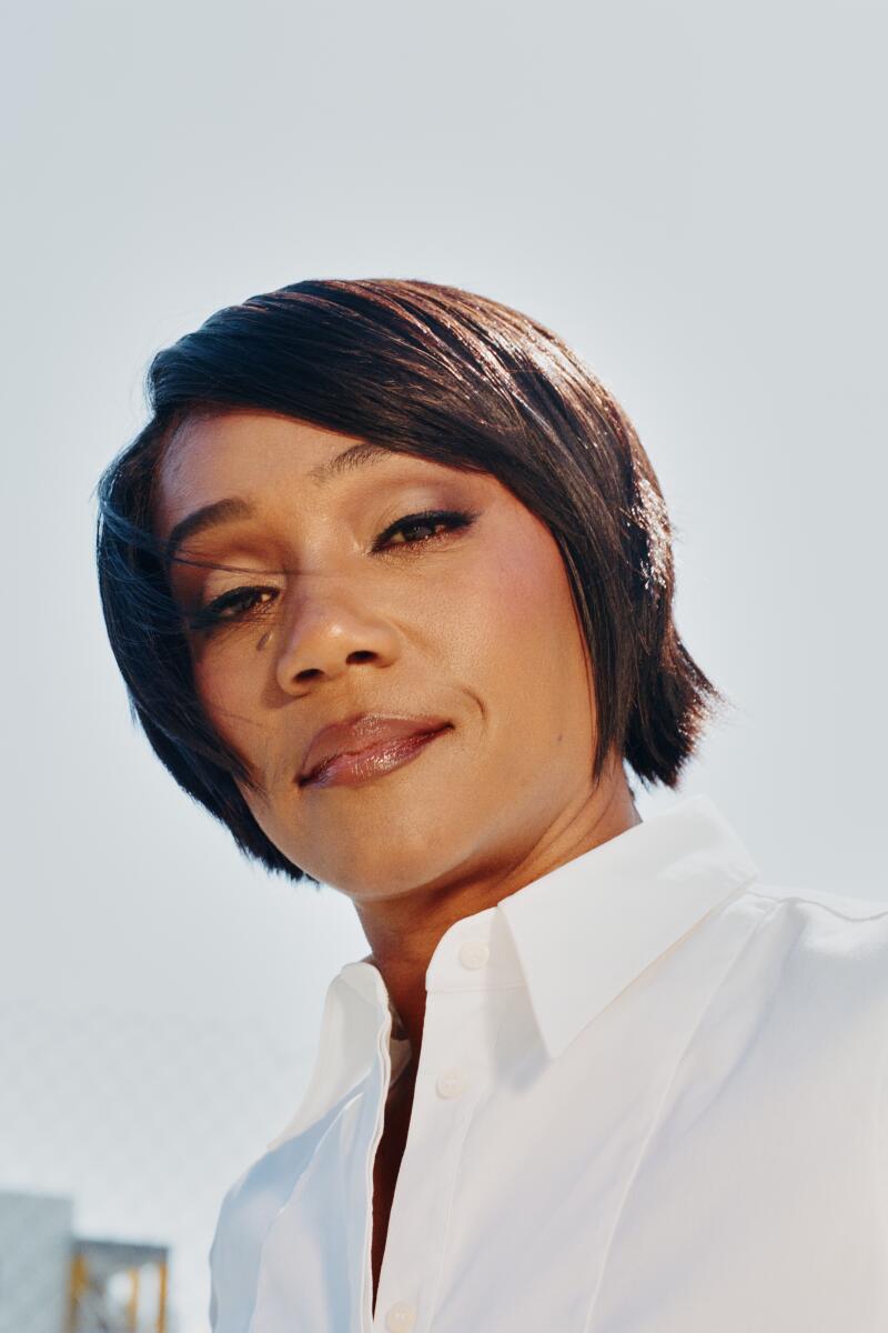 A closeup of Tiffany Haddish with a slight smile and short hair, wearing white