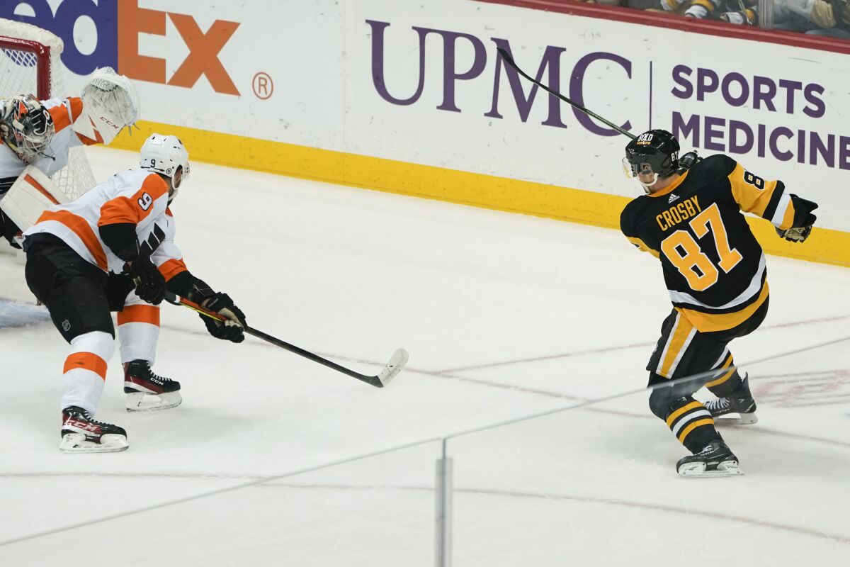 Pittsburgh Penguins' Sidney Crosby (87) scores his 500th NHL career goal on Philadelphia Flyers goaltender Carter Hart, left, during the first period of an NHL hockey game, Tuesday, Feb. 15, 2022, in Pittsburgh. (AP Photo/Keith Srakocic)