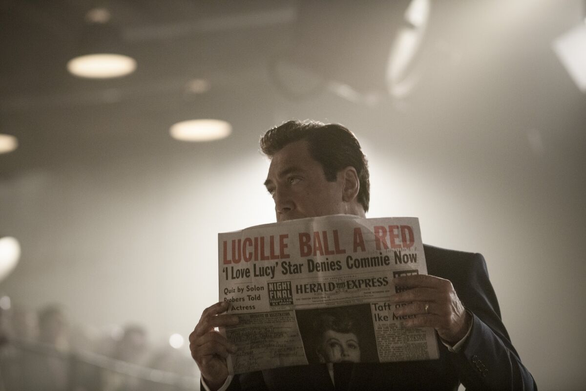 A man holds up a newspaper with the headline "Lucille Ball a Red."