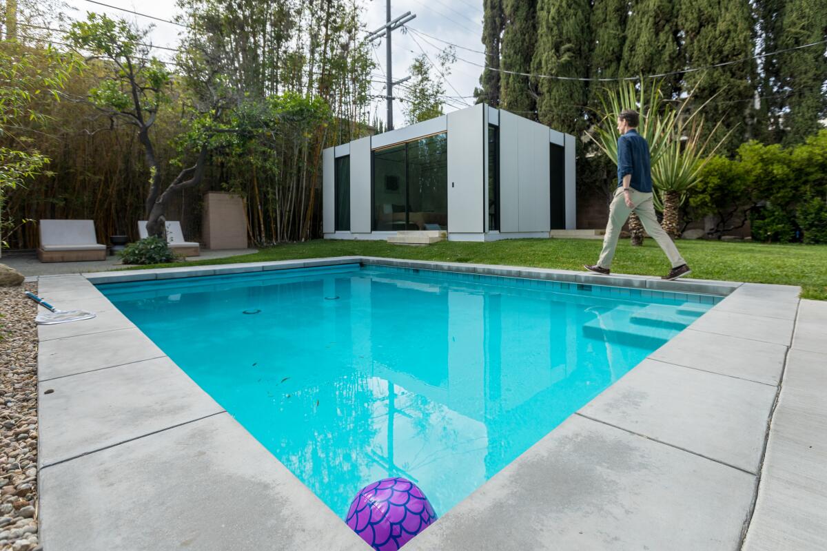 A man walks toward an ADU next to a swimming pool.