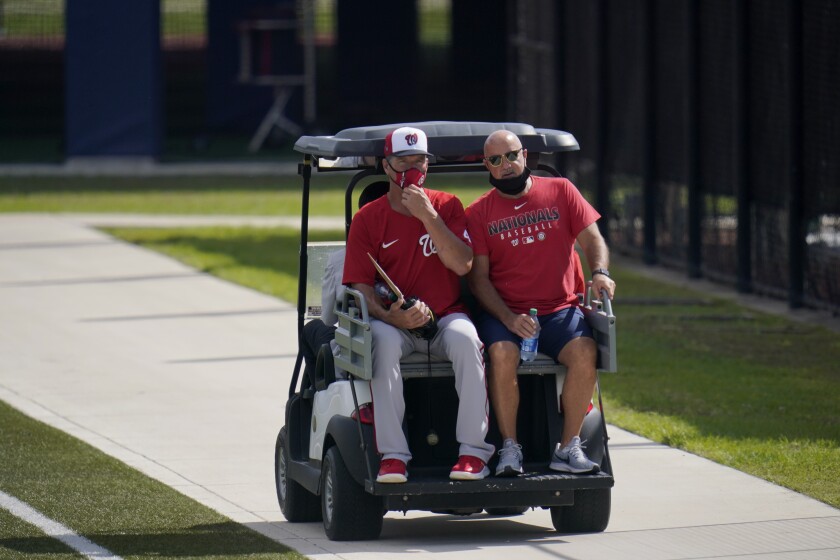 Washington Nationals pitching coach Jim Hickey, left, rides in the back of a golf cart with Nationals general manager Mike Rizzo during spring training baseball practice Thursday, Feb. 25, 2021, in West Palm Beach, Fla. (AP Photo/Jeff Roberson)