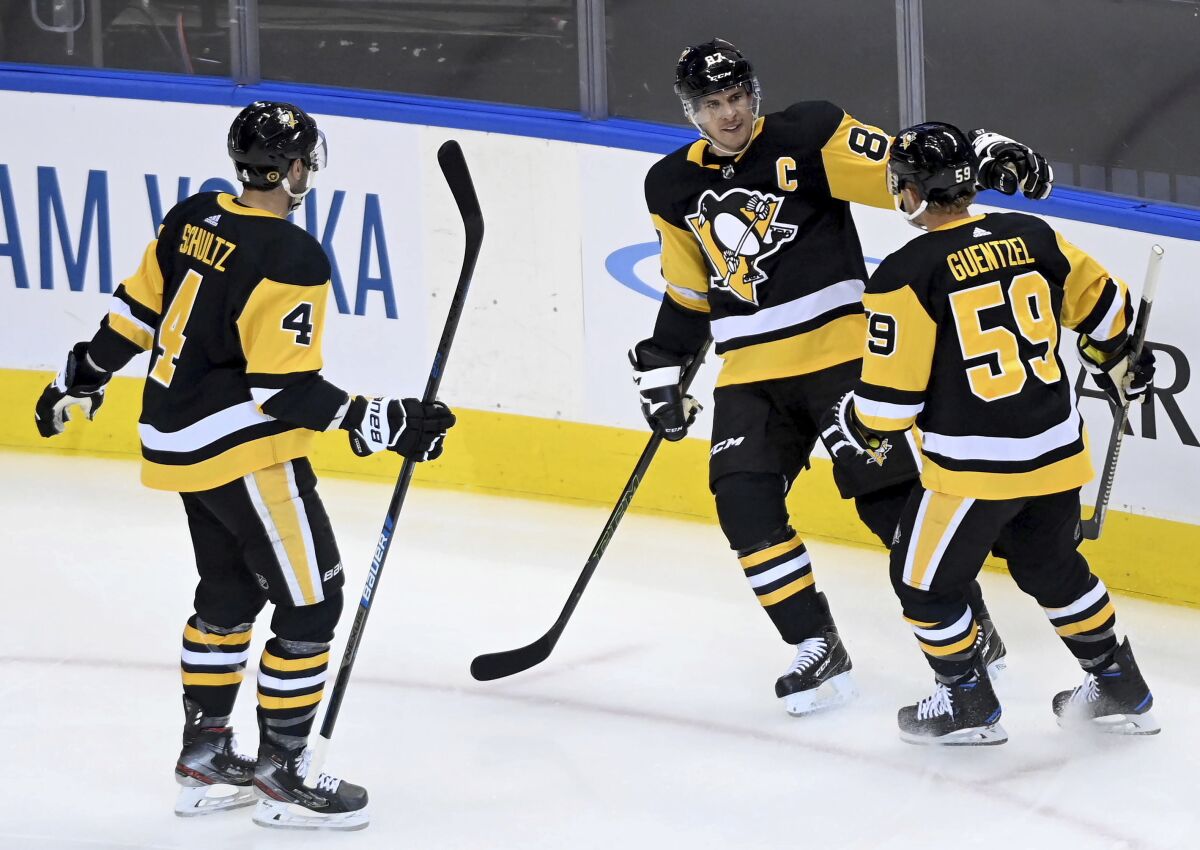 Pittsburgh Penguins center Sidney Crosby (87) celebrates his goal with teammates Justin Schultz (4) and Jake Guentzel (59) during the first period of an NHL hockey playoff game Monday, Aug. 3, 2020 in Toronto. (Nathan Denette/The Canadian Press via AP)
