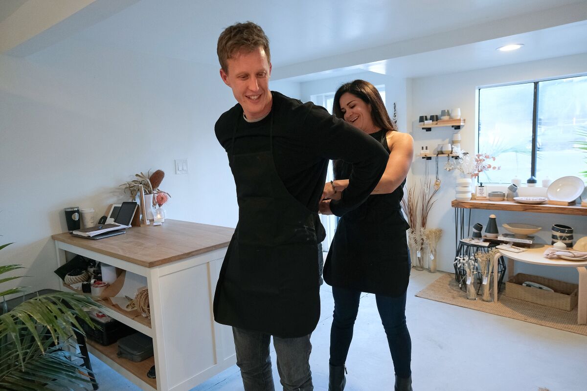 SAN DIEGO, CA-NOVEMBER 13, 2019: Carina helps David put on an apron for their date at CLAY + CRAFT in Encinitas. (Misael Virgen / PACIFIC Magazine)
