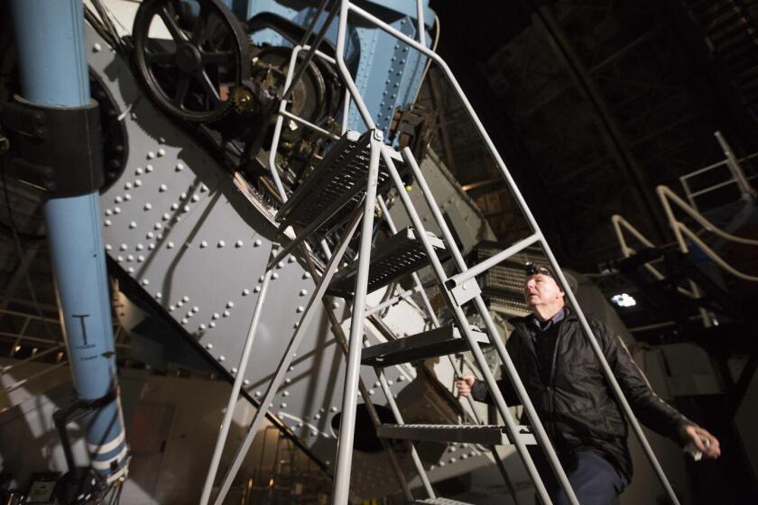 Kenneth Evans climbs a ladder to work on the century-old 100-inch reflector telescope at the Mt. Wilson Observatory.