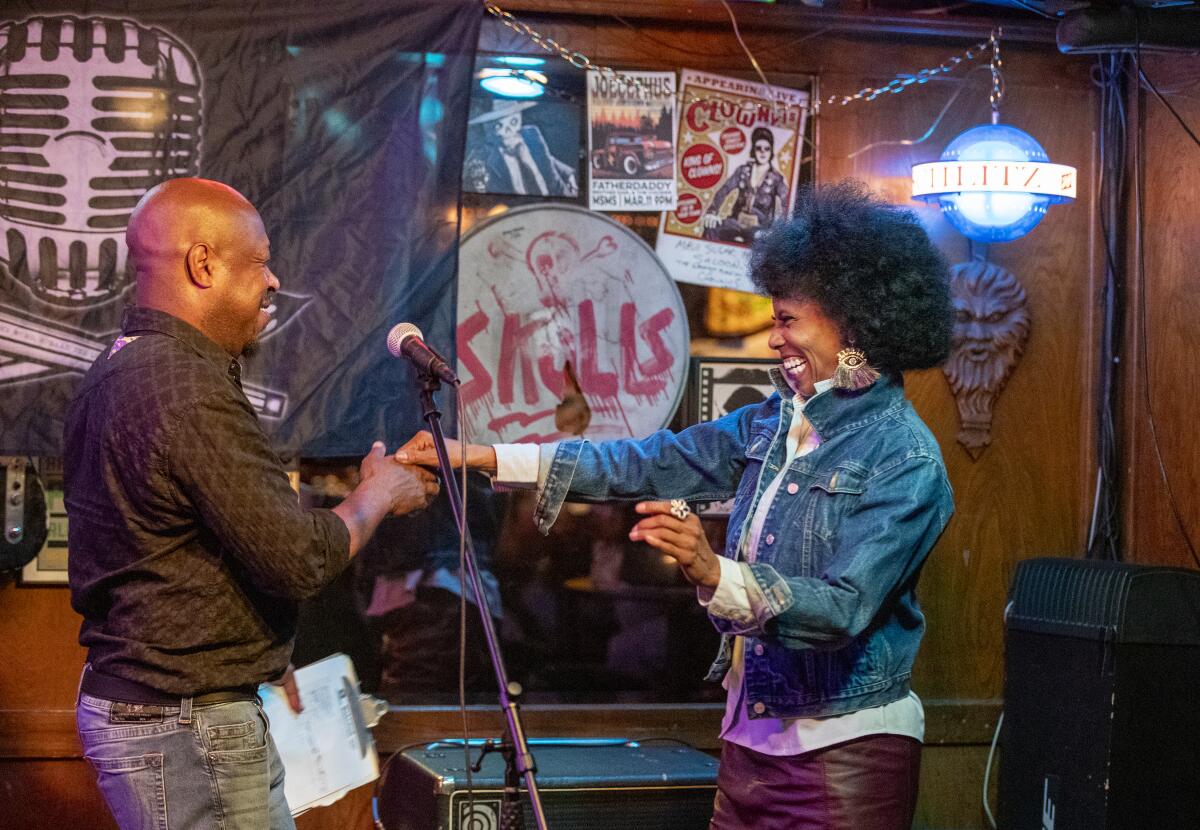 V, a comedian, right, is greeted and introduced by Jerome Anderson, at the Maui Sugar Mill Saloon in Tarzana.