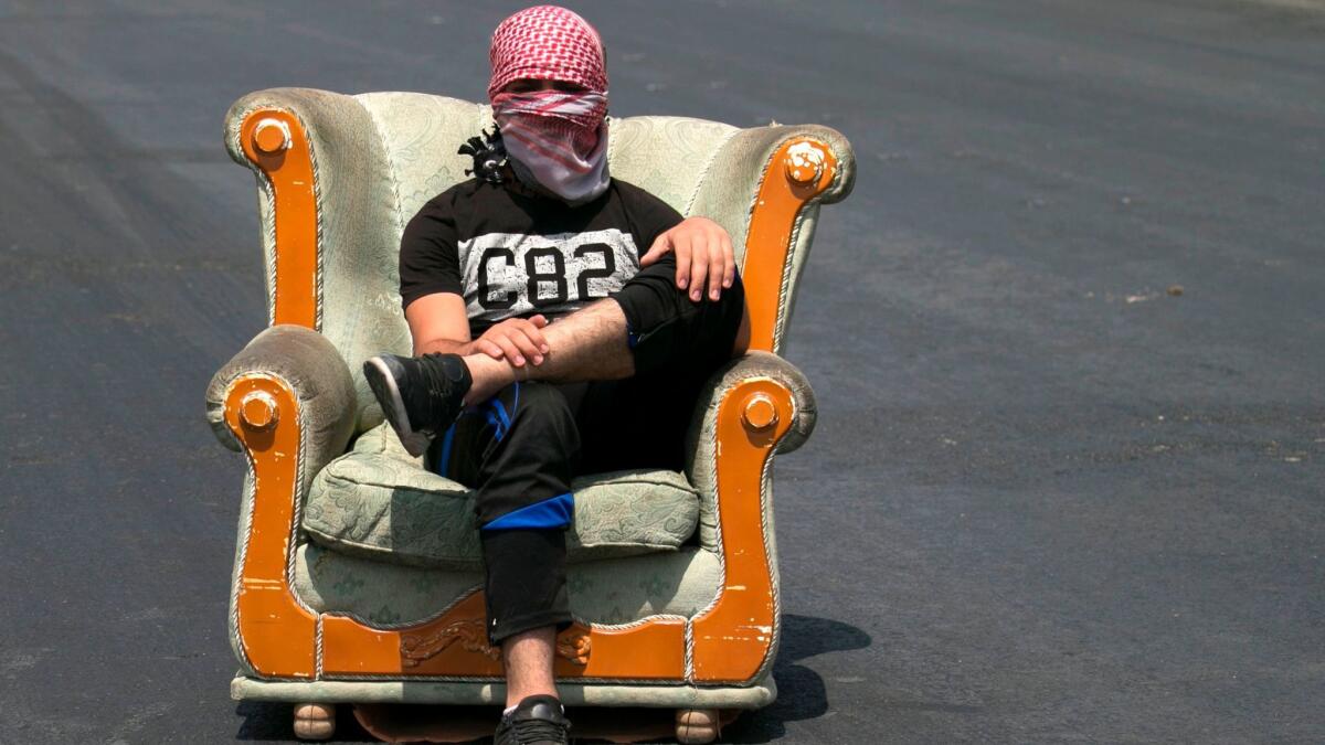 A Palestinian protester sits along the road during a demonstration at the Hawara checkpoint, south of the West Bank city of Nablus, on July 21, 2017.