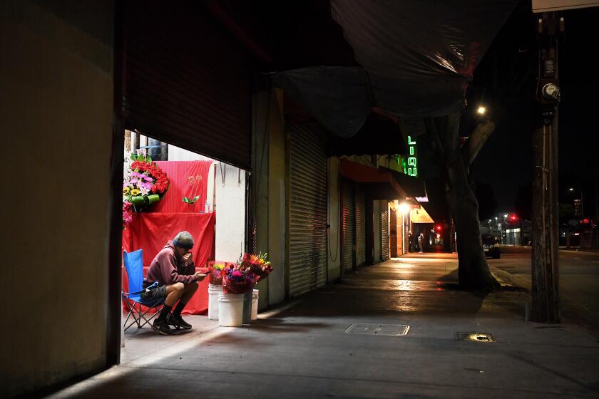 LOS ANGELES, CALIFORNIA APRIL 15, 2020-At 9:45 pm, Johnny Guerrero sells flowers at his parents buisness Novarose By Hilda on San Pedro St. in Downtown Los Angeles Tuesday night. Guerrero says while the other flower shops are closed they stay open in hopes of more sales. He also says it's a tough time to get flowers in stock since the suppliers are closed due to the Coronavirus. (Wally Skalij/Los Angeles Times)