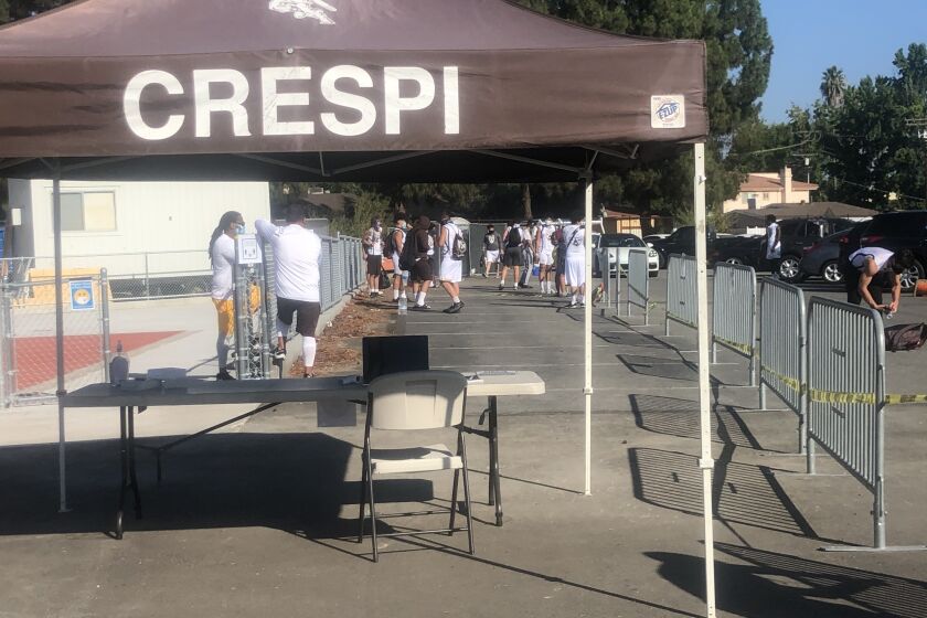 Players wait to check in for a temperature check at Crespi High in Encino.
