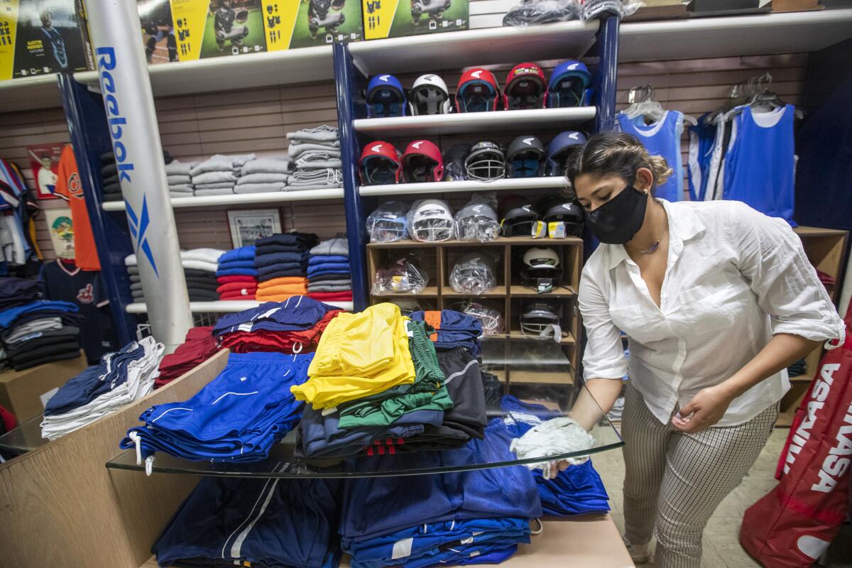 Daniela Prieto, an employee at Deportes Prieto in Boyle Heights, disinfects inside the store.