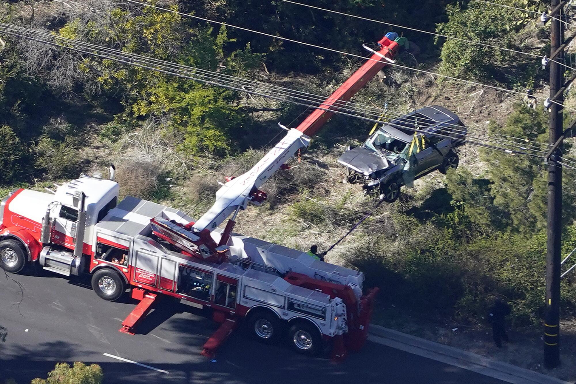 Workers move a vehicle after a rollover accident involving golfer Tiger Woods in Rancho Palos Verdes