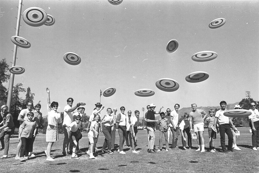 People stand in a line and toss Frisbees toward the camera.