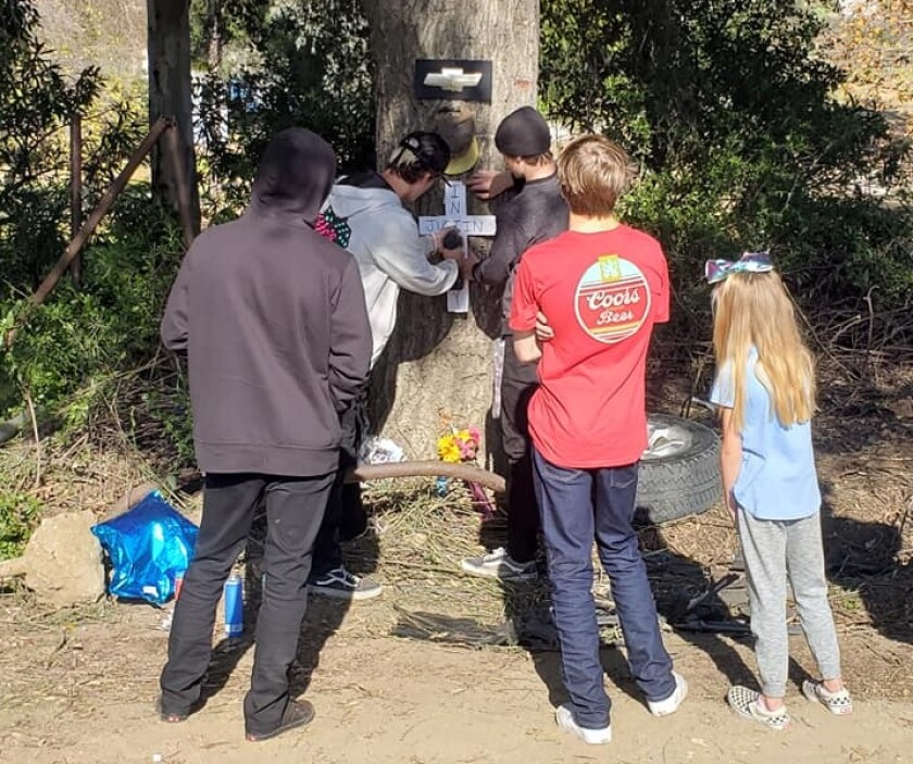 A group of young people gather Sunday at a growing memorial at the site where one 16-year-old boy was killed and another was gravely injured late Saturday night in Lakeside.