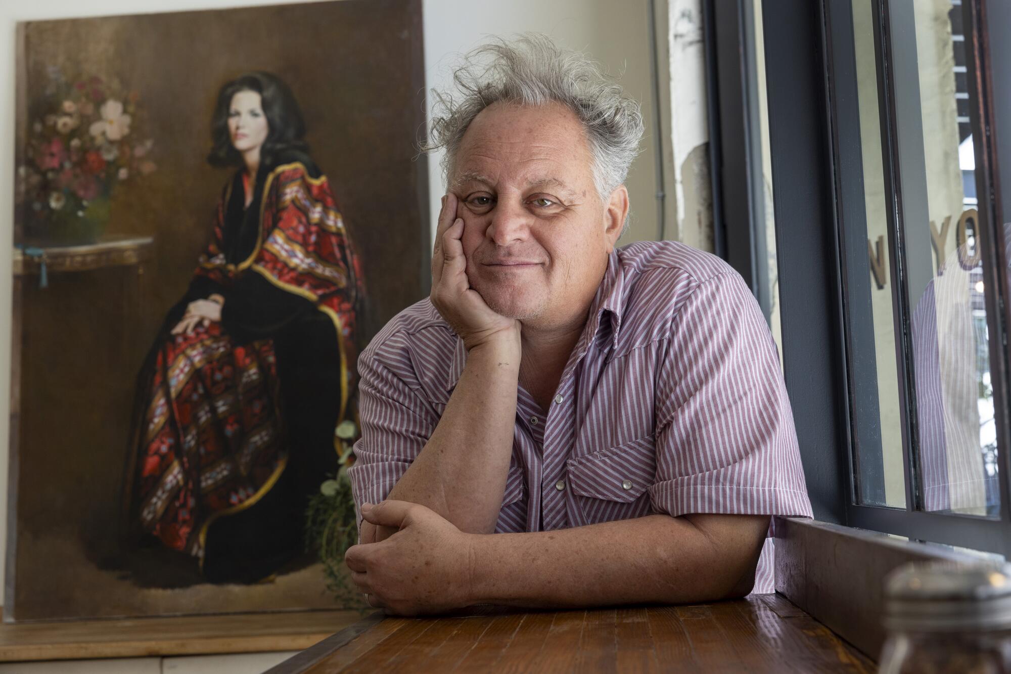 Chris Bianco sits for a portrait with a 1970 painting made by his father Leonard 