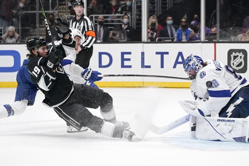 Los Angeles Kings left wing Alex Iafallo, left, slides into Tampa Bay Lightning goaltender Andrei Vasilevskiy, right, as he tries to score while right wing Mathieu Joseph defends during the second period of an NHL hockey game Tuesday, Jan. 18, 2022, in Los Angeles. (AP Photo/Mark J. Terrill)