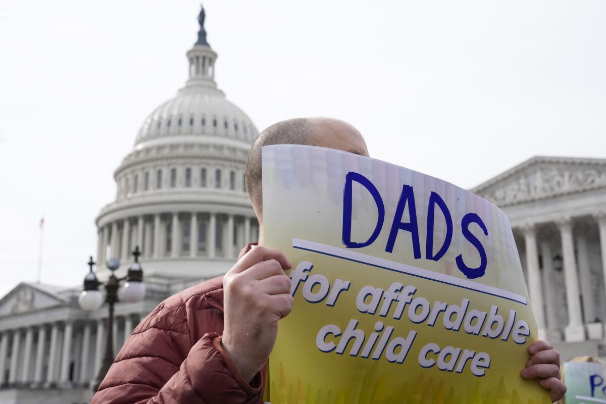 A person holds a sign reading "Dads for affordable child care" outside the U.S. Capitol.