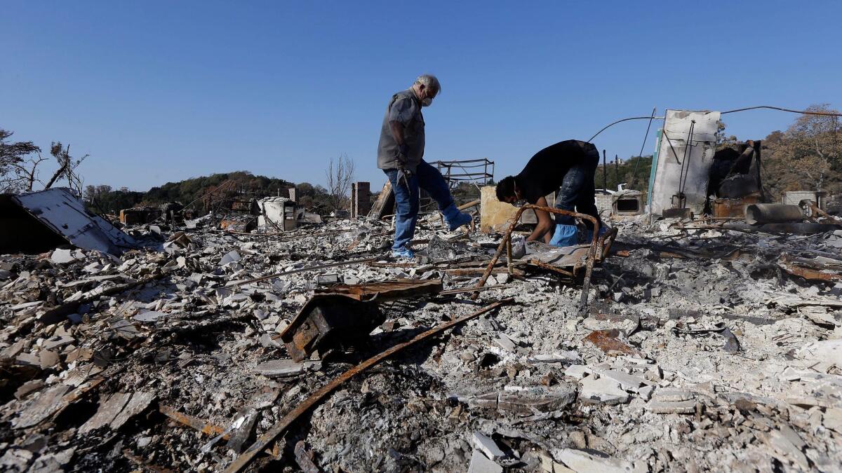 Timothy Lillyquist, left, and Johnny Quirarte on Oct. 31 search through their friend Mary Burns' home that was destroyed by wildfires in Santa Rosa, Calif.
