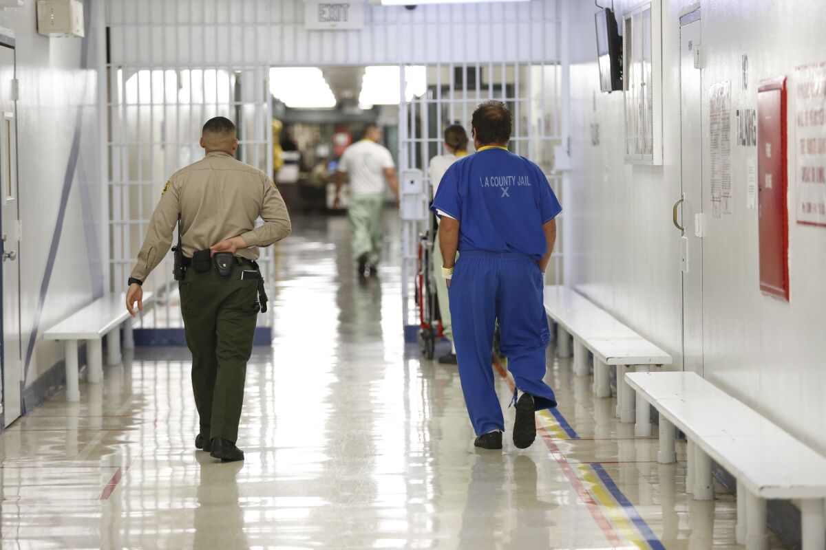 A Los Angeles County sheriff's employee walks with an inmate.