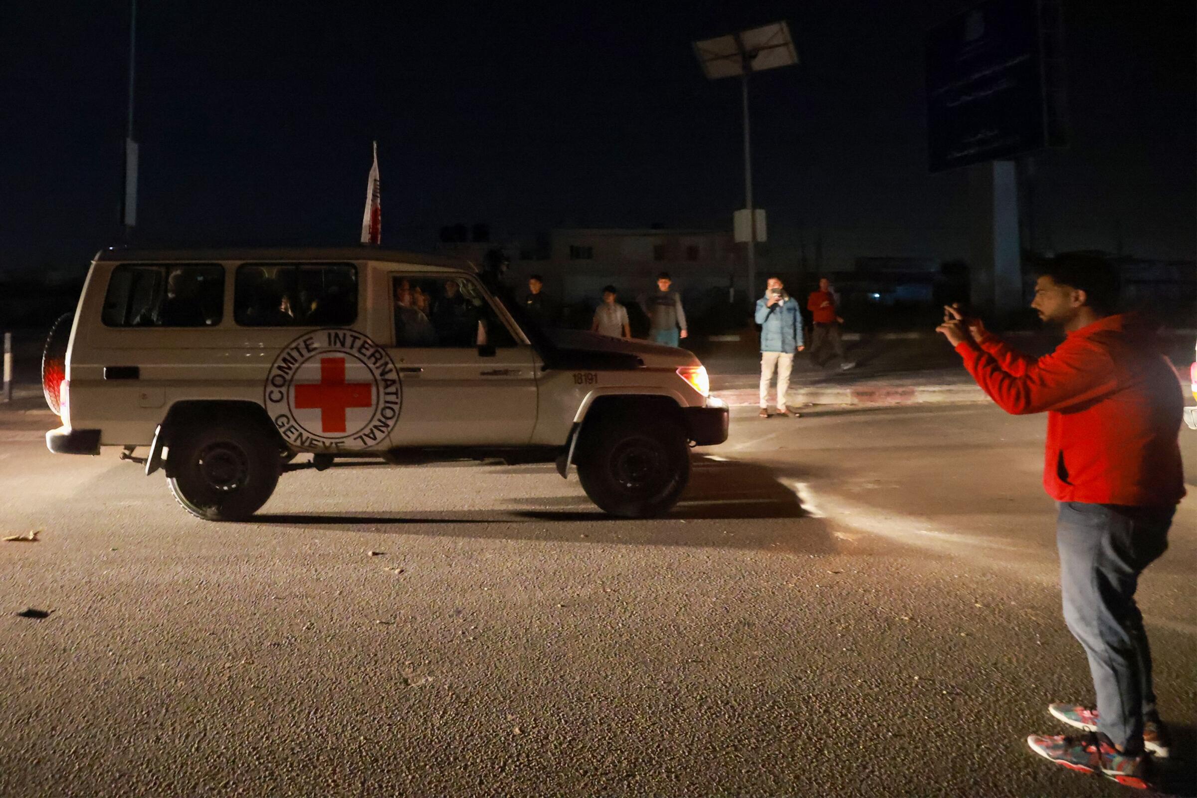 A Red Cross vehicle drives at night.