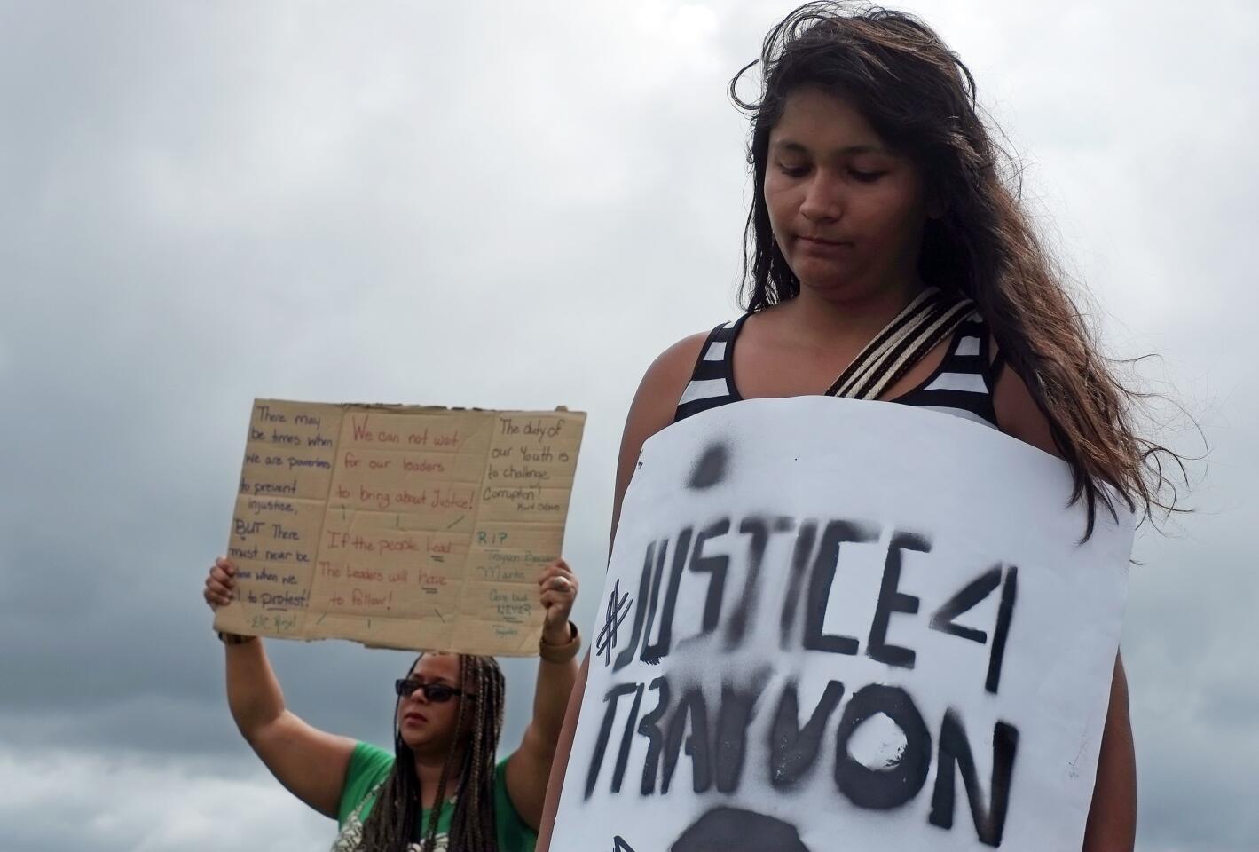 Kari Reay, left, and Estefania Galvis, right, stand with a small group of protesters along U.S. Highway 17-92 in Sanford in front of the courthouse on Sunday, July 14, 2013, the day after George Zimmerman was found not guilty of the murder of Trayvon Martin. (Jacob Langston/Orlando Sentinel)
