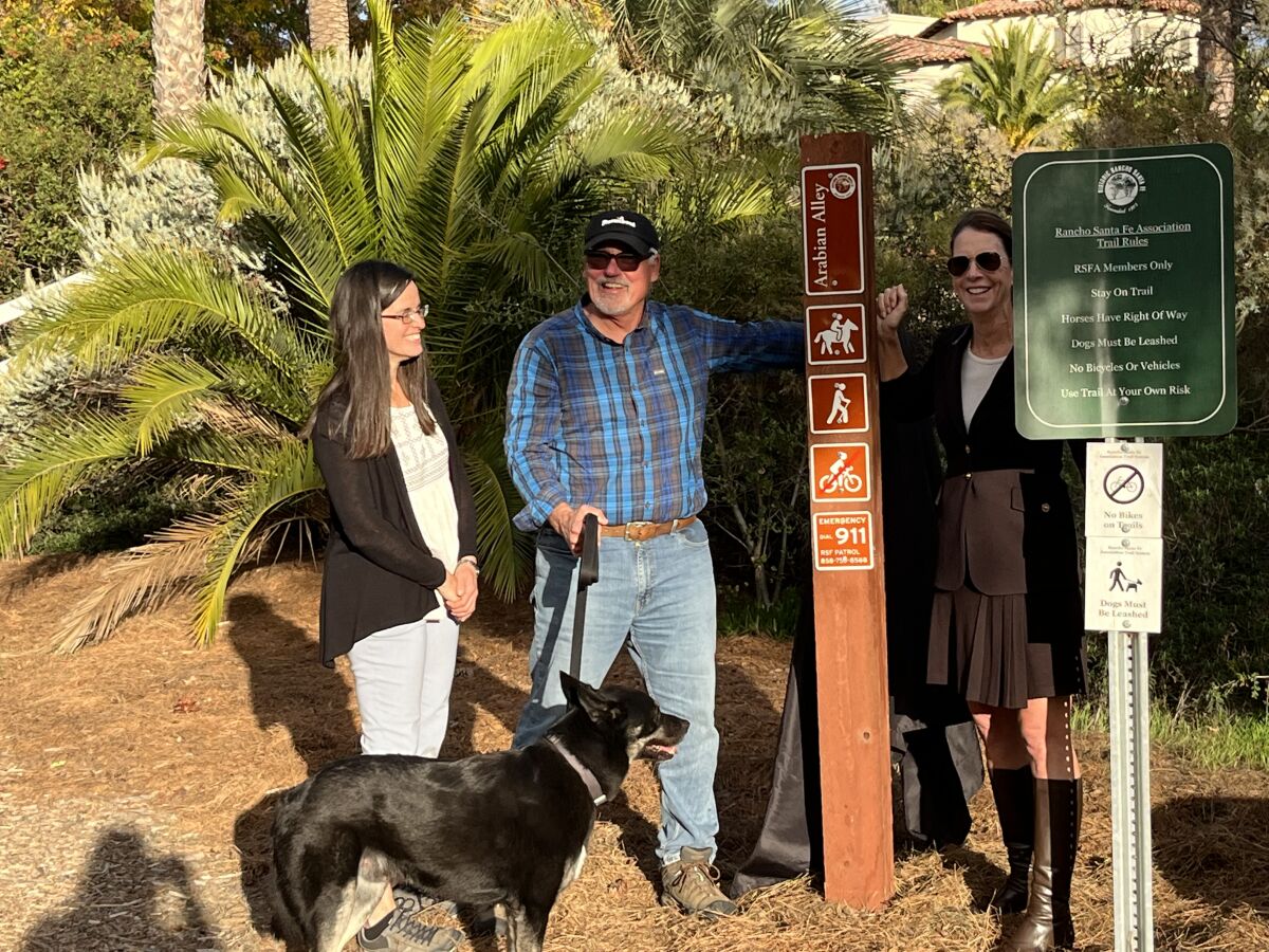 Ilia Christy, Jeff Simmons and Deana Ingalls and Sam the dog with the new Arabian Alley trail marker.
