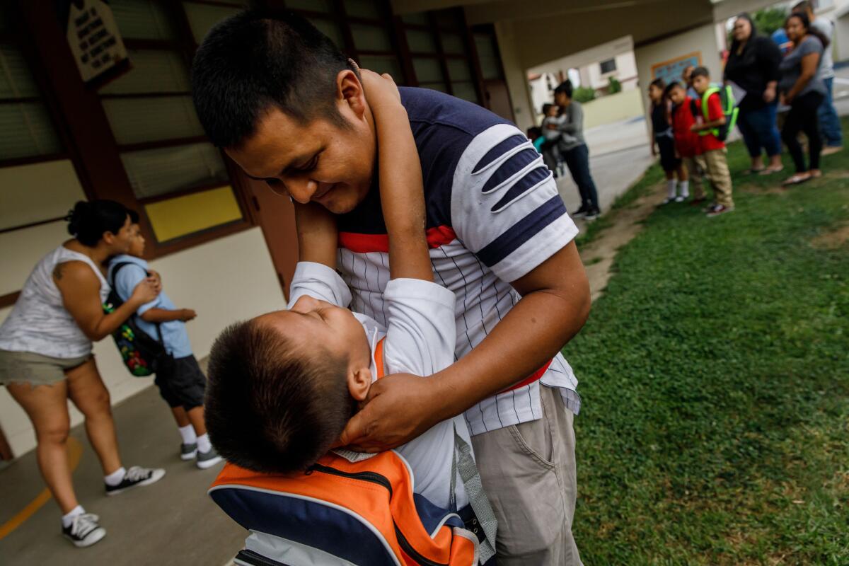 Jefferson Che Pop embraces his father, Hermelindo Che Coc, as they wait for Jefferson's teacher to arrive outside his classroom on the first day of school.