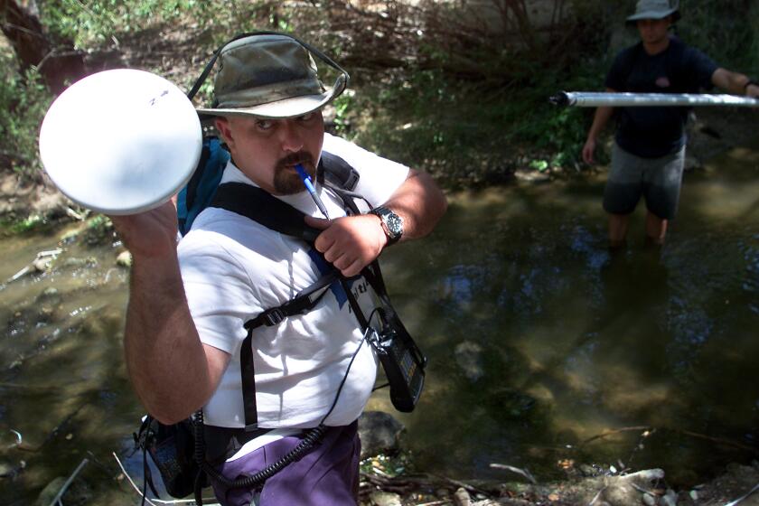 George Wilhelm x23486 –– – Heal the Bay stream team coordinator Mark Abramson, left, reaches for the antenna of his global satellite positioning system after taking measurements at a small pool on Las Virgenes Creek. For the past year and a half, Heal the Bay has been sending volunteers out to various parts of 110–square–mile area that makes up the Malibu Creek watershed to test water samples and seach for possible sources of pollution that trickle downstream.