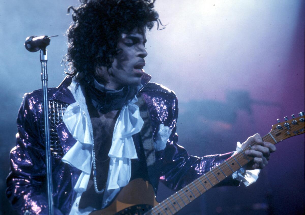 Wearing a ruffled shirt and shiny purple jacket, Prince performs at the Forum on Feb. 19, 1985, in Inglewood.