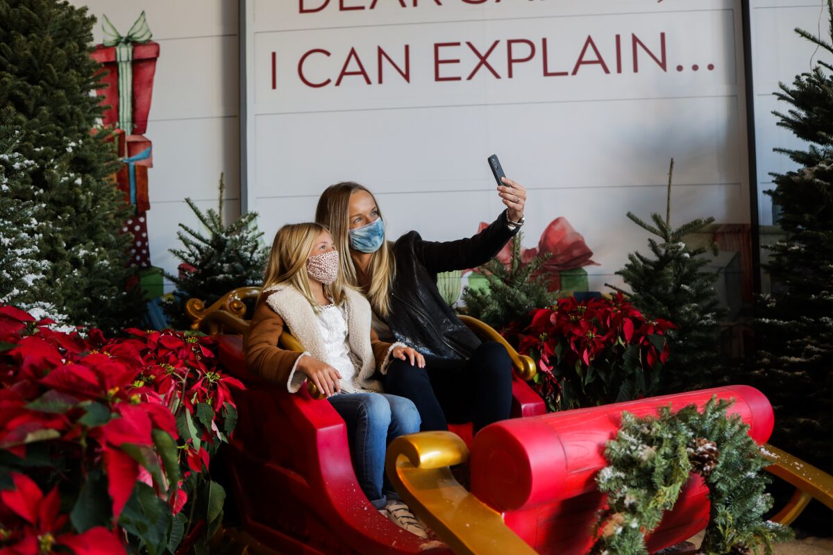 A woman and a child take a selfie in a colorful holiday sleigh